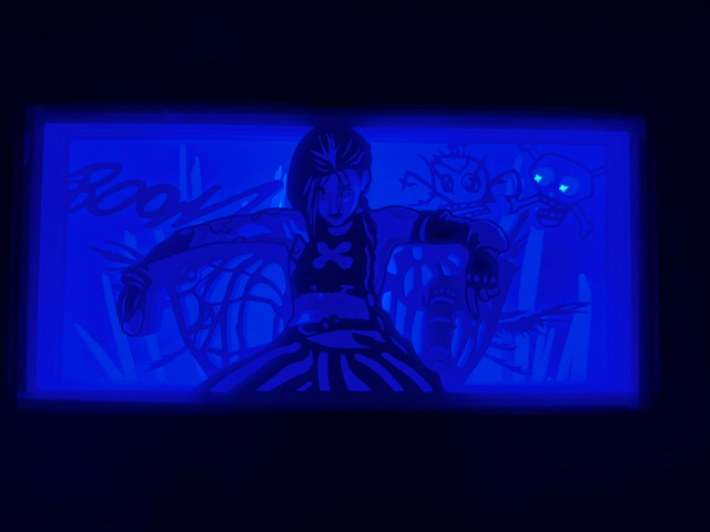 Jinx, League of Legends, LoL, Arcane, série Arcane, Netflix, Piltover, Zaun, sœur de Vi, Powder, héroïne déjantée, flingues, mitraillette, lance-roquettes Fishbones, personnage culte, champion LoL, univers steampunk, jeu vidéo culte, Riot Games, anti-héroïne, tableau lumineux, lightbox, shadowbox, cadre lumineux, papier découpé, art lumineux, décoration murale, idée cadeau gamer, déco geek, cadeau fan Arcane, otaku