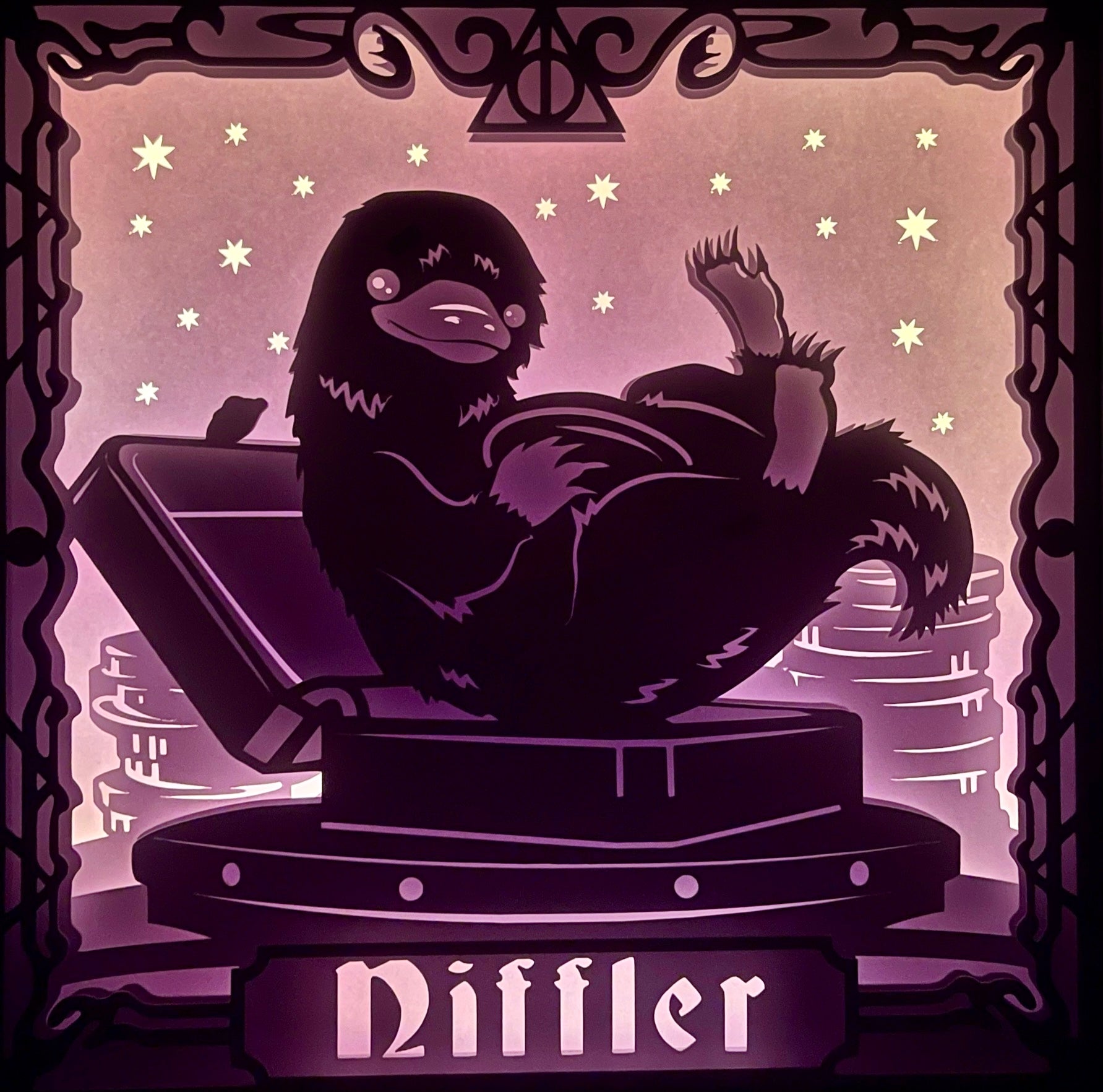 Niffleur, Nifler, Niffler Harry Potter, Les Animaux Fantastiques, Fantastic Beasts, J.K. Rowling, créature magique, voleur de trésors, poche ventrale, or et bijoux, Norbert Dragonneau, univers magique, saga Harry Potter, film Les Animaux Fantastiques, magie, créature attachante, monde des sorciers, personnage culte, tableau lumineux, lightbox, shadowbox, cadre lumineux, papier découpé, art lumineux, décoration murale, idée cadeau geek, déco magique, cadeau fan Harry Potter